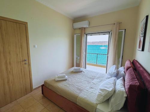 a bedroom with a bed with a view of the ocean at Costalia Seafront Apt in Elounda