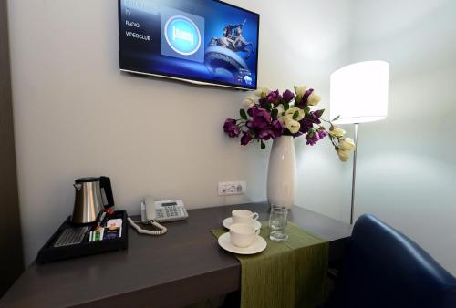 a desk with a vase of flowers and a telephone at Alexandar Square Boutique Hotel in Skopje