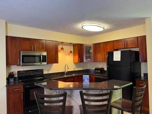 a kitchen with wooden cabinets and a black refrigerator at Put-in-Bay Poolview Condo #5 in Put-in-Bay