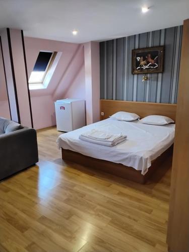 a bedroom with a large bed with white sheets at Hotel Mehdjarel in Shumen
