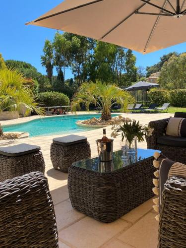 une table et des chaises avec un parasol à côté d'une piscine dans l'établissement Le Paradou, à Carqueiranne