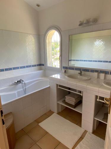 une salle de bain avec une baignoire, un lavabo et un miroir dans l'établissement Le Paradou, à Carqueiranne