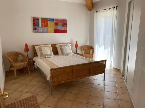 une chambre avec un lit et deux chaises et une fenêtre dans l'établissement Le Paradou, à Carqueiranne