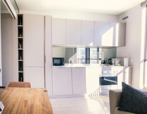 a kitchen with white cabinets and a wooden table at Le Chic - Luxury meets Lifestyle in Johannesburg