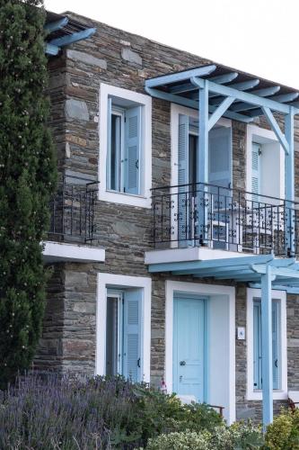 a brick building with blue doors and a balcony at Perla Pool Hotel Andros in Ménites