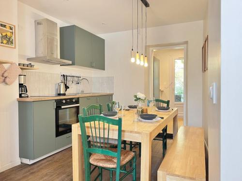 une cuisine avec une table en bois et des armoires vertes dans l'établissement Le St-Hilaire, House in the city center with patio with parking, à Poitiers