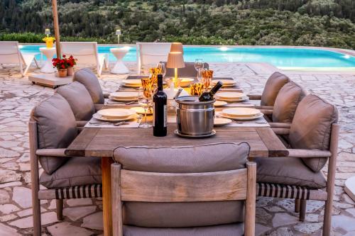 a table set for a dinner party with a view of a pool at Kronos Estate Lefkada - 5 star luxury in Mikros Gialos