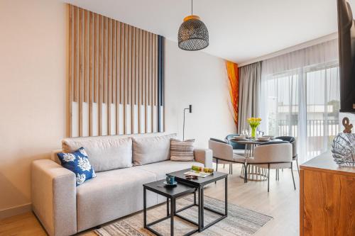 a living room with a couch and a table at Resort Baltic Waves Apartments - Basen, Sauna in Międzyzdroje