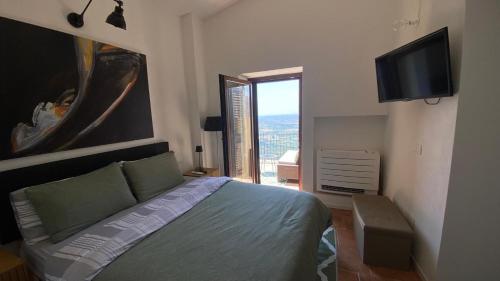 a bedroom with a bed and a flat screen tv at La Stalla e il Fienile suites viste mozzafiato in Norma