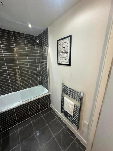 City View One Bedroom Apartment في ليفربول: حمام مع حوض استحمام وأرضية من البلاط