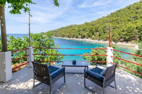 two chairs and a table on a balcony overlooking the water at House Herta in Gdinj