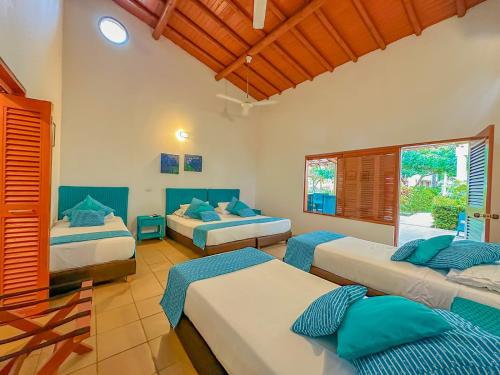 a bedroom with three beds and two windows at Hotel Chiniu in Palomino