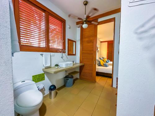 a bathroom with a toilet and a sink and a bed at Hotel Chiniu in Palomino