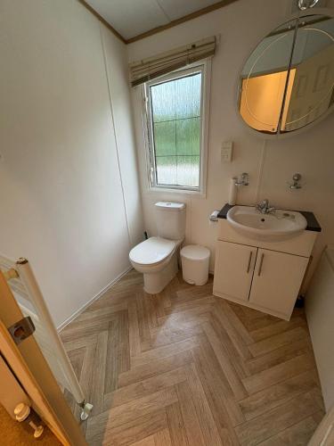 a bathroom with a toilet and a sink and a mirror at Gbk caravans in Rhyl