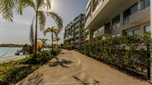 a sidewalk next to a beach with palm trees and a building at Baia Kristal in Cartagena de Indias