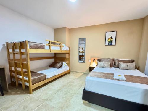a bedroom with two beds and a bunk bed at Casa Flor Hostel & Drinks in Ríohacha