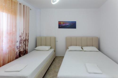 two beds in a room with white walls and a window at Spacious 2 bedroom apartment in Durres Beach in Durrës