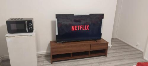 a flat screen tv sitting on top of a wooden entertainment center at Modern Apartment in Southeast London in Plumstead