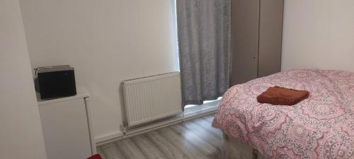 a bedroom with a pink bed and a television at Modern Apartment in Southeast London in Plumstead