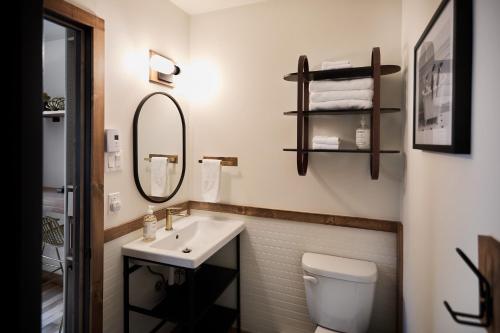 a bathroom with a sink and a toilet and a mirror at Motel Boutique Hygge in Baie-Saint-Paul