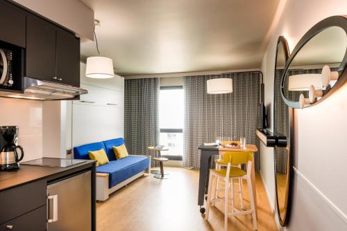 a kitchen and a living room with a blue couch at Aparthotel Adagio access Colombes La Défense in Colombes
