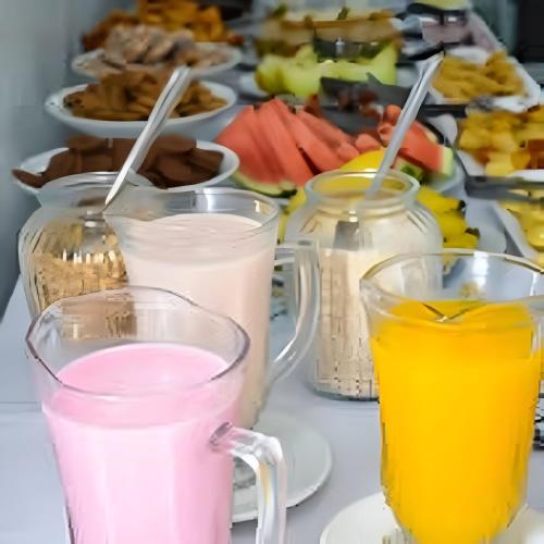 een tafel met drie glazen melk en een bord met eten bij Hotel Ipê in São Luís Gonzaga