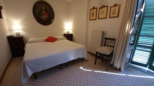 a bedroom with a bed and a chair and a window at Casa Laura in Madonna della Scala