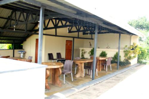 a patio with tables and chairs under a roof at Bar Lyec Safari Lodge in Pakwach East