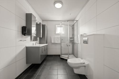 a white bathroom with a toilet and a sink at Kinn Hotell Florø in Florø