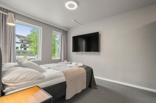 a bedroom with a bed and a flat screen tv at Kinn Hotell Florø in Florø