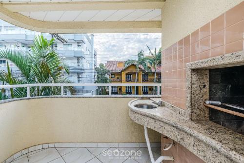 ボンバスにあるApto 2Q c varanda a 220m da praia de Bombas FDL103のシンクと暖炉のあるバルコニー