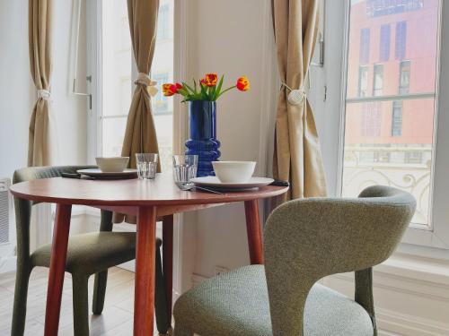une table avec deux chaises et un vase bleu avec des fleurs dans l'établissement Suite Luna - Check in h24 - proche centre ville, à Lyon