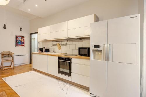  La cuisine est équipée de placards blancs et d'un réfrigérateur. dans l'établissement Bella Nissa Bnb - AC wifi - cosy - 2 bedrooms, à Nice
