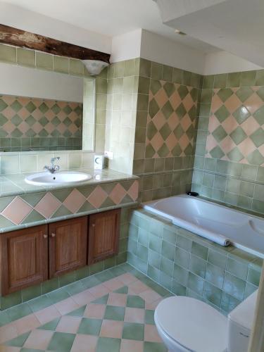 a bathroom with a tub and a sink and a toilet at Le Presbytère - La Trêverie in Le Torquesne