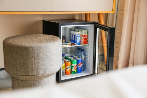a small refrigerator with drinks in it next to a chair at The Red - a GiGi Residence in Mājid Abū Zayd