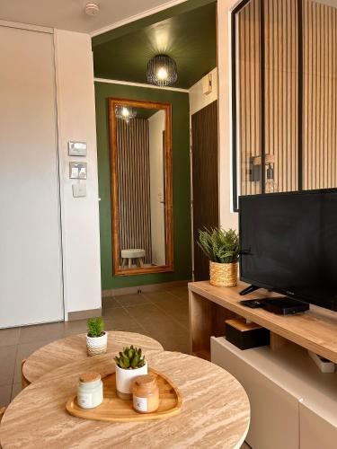 a living room with a table and a flat screen tv at Un cocon tout confort à La Rochelle - proche gare & plages in La Rochelle