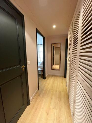 a hallway with a black door and wooden floors at Cœur de Saint-Tropez - 2 chambres - Terrasse - Parking in Saint-Tropez