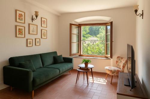 sala de estar con sofá verde y ventana en Il suono del fiume, en Bagnone