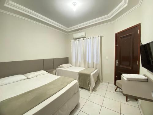 a hotel room with two beds and a chair at Pousada DONA LÍDIA in Campo Mourão