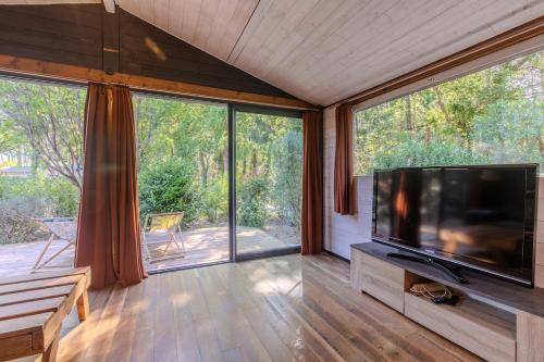 Il comprend un salon doté d'une télévision à écran plat et d'une grande fenêtre. dans l'établissement Charmant chalet proche Hossegor, à Saubion