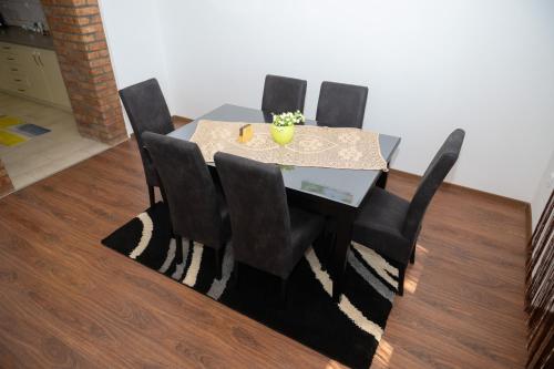 a dining room table with four black chairs and a table at Kuća NP in Bačka Topola