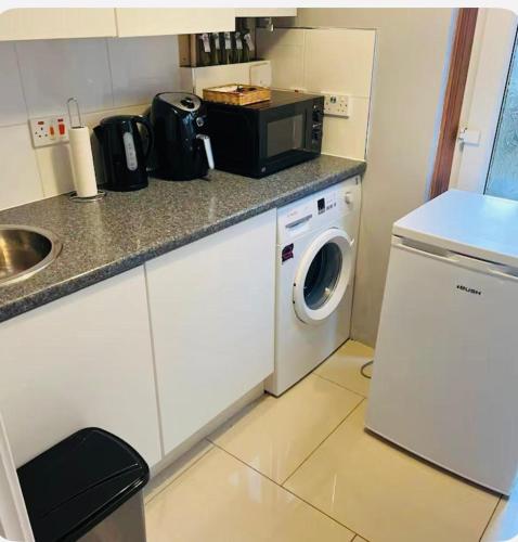 a kitchen with a washing machine and a microwave at Bank West in Edinburgh