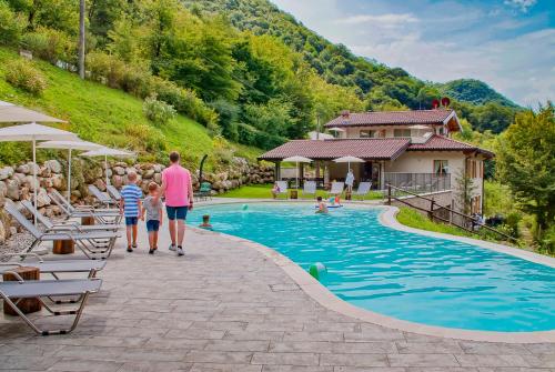 a woman and two children walking by a swimming pool at La Fontanina in Vobarno