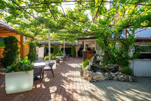 a patio with tables and chairs and a tree at La Borsanu in Năsăud