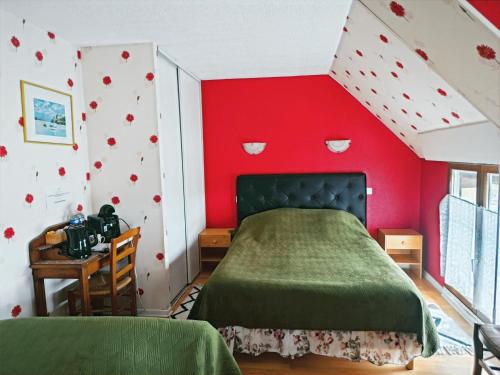 a bedroom with a red wall with a bed and a desk at Chambres Les Salles in Beauvoir
