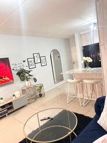 a living room with a glass table and a kitchen at Fully Furnished 3 bedroom apartment rental in Roodepoort