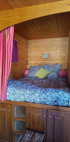 un lit dans une cabane en bois avec un pare-lit dans l'établissement La roulotte la tribu deschpouss, à Saint-Christophe-en-Boucherie