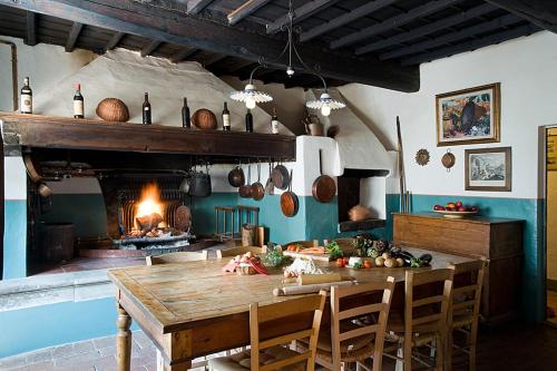 a kitchen with a wooden table and a fireplace at Fattoria di Rignana in Greve in Chianti