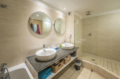 een badkamer met 2 wastafels, een bad en spiegels bij Le Nid - Cosy Plage & Confort - Wiskeys in Saint-Paul