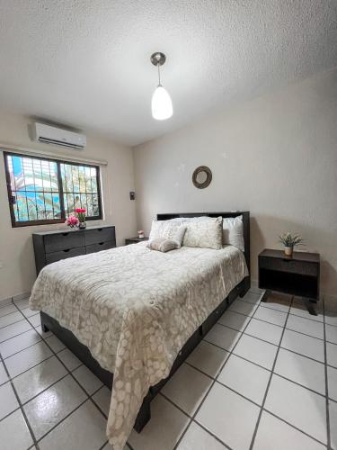 a bedroom with a large bed and two tables and a window at Rainbow Suites in Cozumel